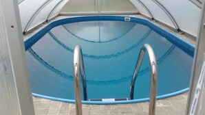 A swimming pool with a curved edge and a ladder leading into it. - Penzion Mona (Bela pod Pradedem)