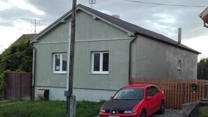 A single-story house with a paved driveway and a red car parked in front. - Apartmany Halex 4 (Bojná)