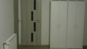 A room with a wooden floor, white walls, a door with a vertical black stripe, and a white wardrobe with two doors. - Apartmany Halex 4 (Bojná)