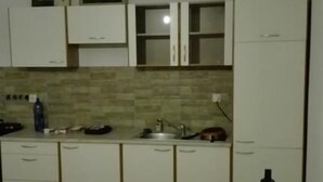 A kitchen with white cabinets, a tiled backsplash, a sink, and a vacuum cleaner. - Apartmany Halex 4 (Bojná)