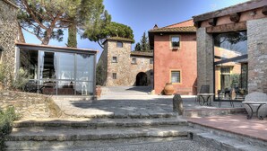 A stone building with a tower, a glass structure, and outdoor seating. - Salvadonica - Borgo del Chianti (San Casciano in Val di Pesa)