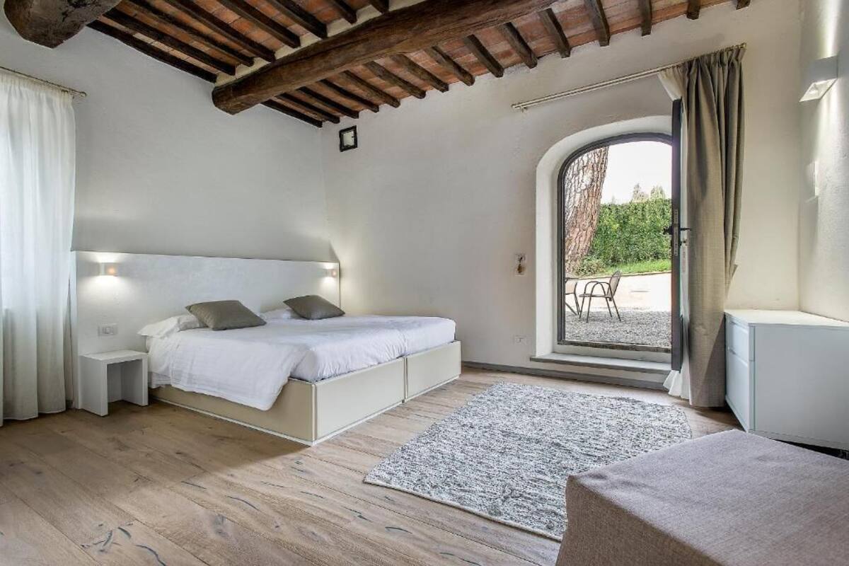 A bedroom with a bed, bedside tables, a rug, and a view of the outdoors.