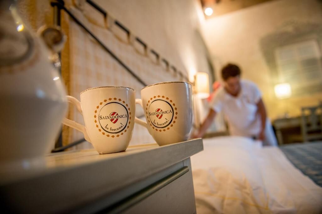 Two coffee cups with 'Salvadonica' branding on a table in a hotel room.