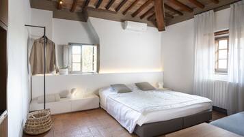A bedroom with a bed, bedside tables, a hanging light fixture, a window, and a ceiling fan.