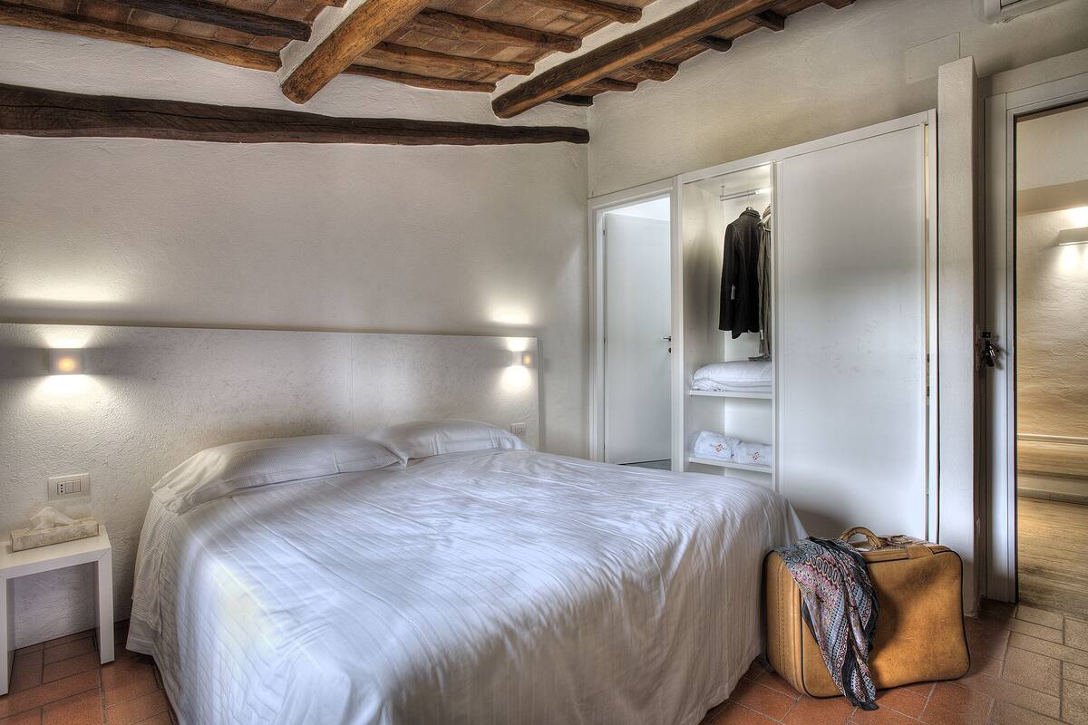 A bedroom with a bed, bedside table, wardrobe, and a suitcase.