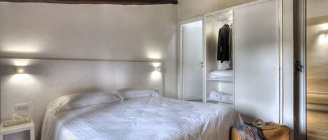 A bedroom with a bed, bedside table, wardrobe, and a suitcase.