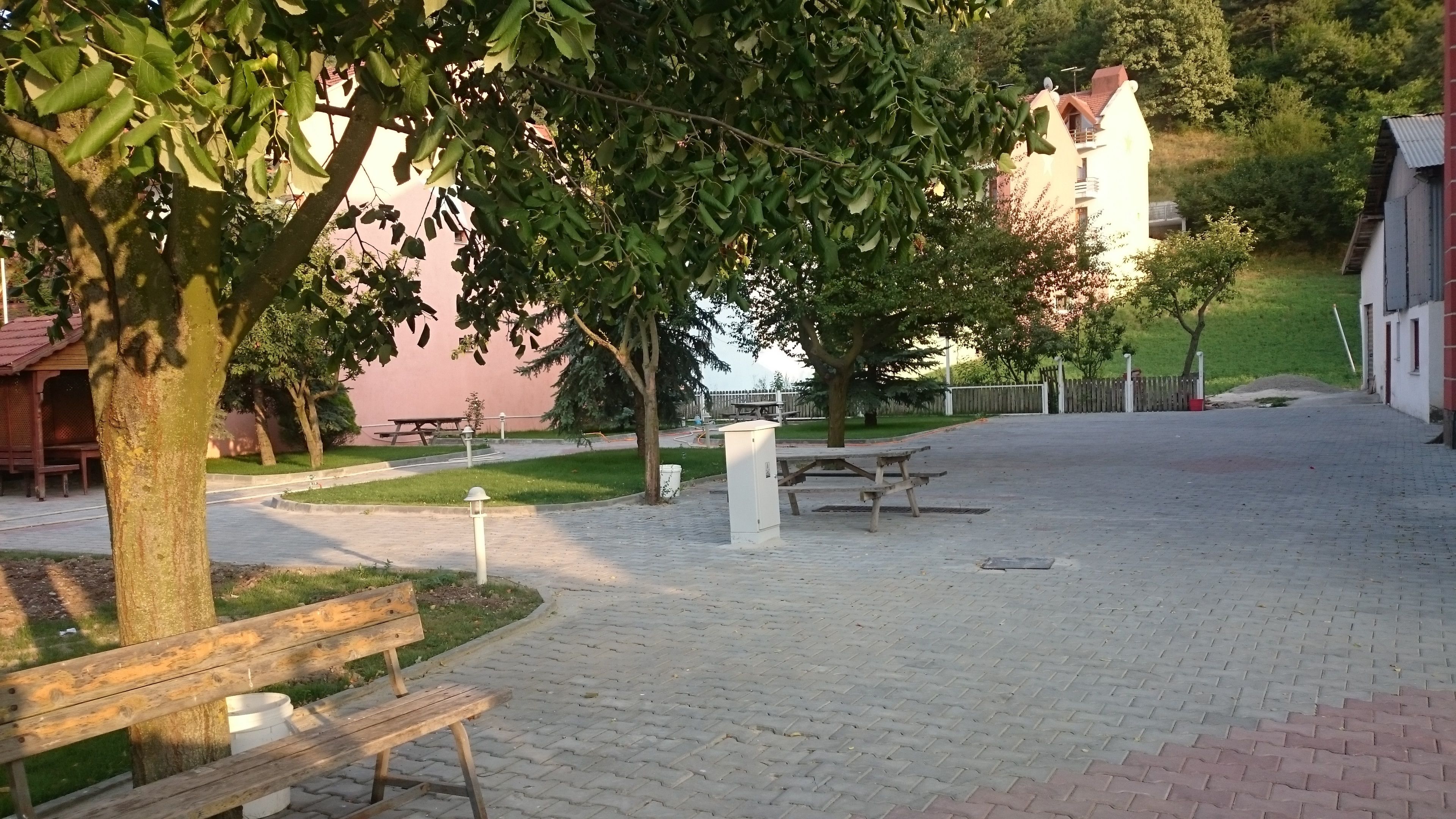 Un patio empedrado con bancos, una mesa de picnic y un armario técnico blanco.
