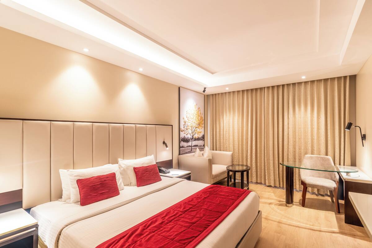 Quarto de hotel moderno com uma cama grande, uma escrivaninha e uma cadeira.