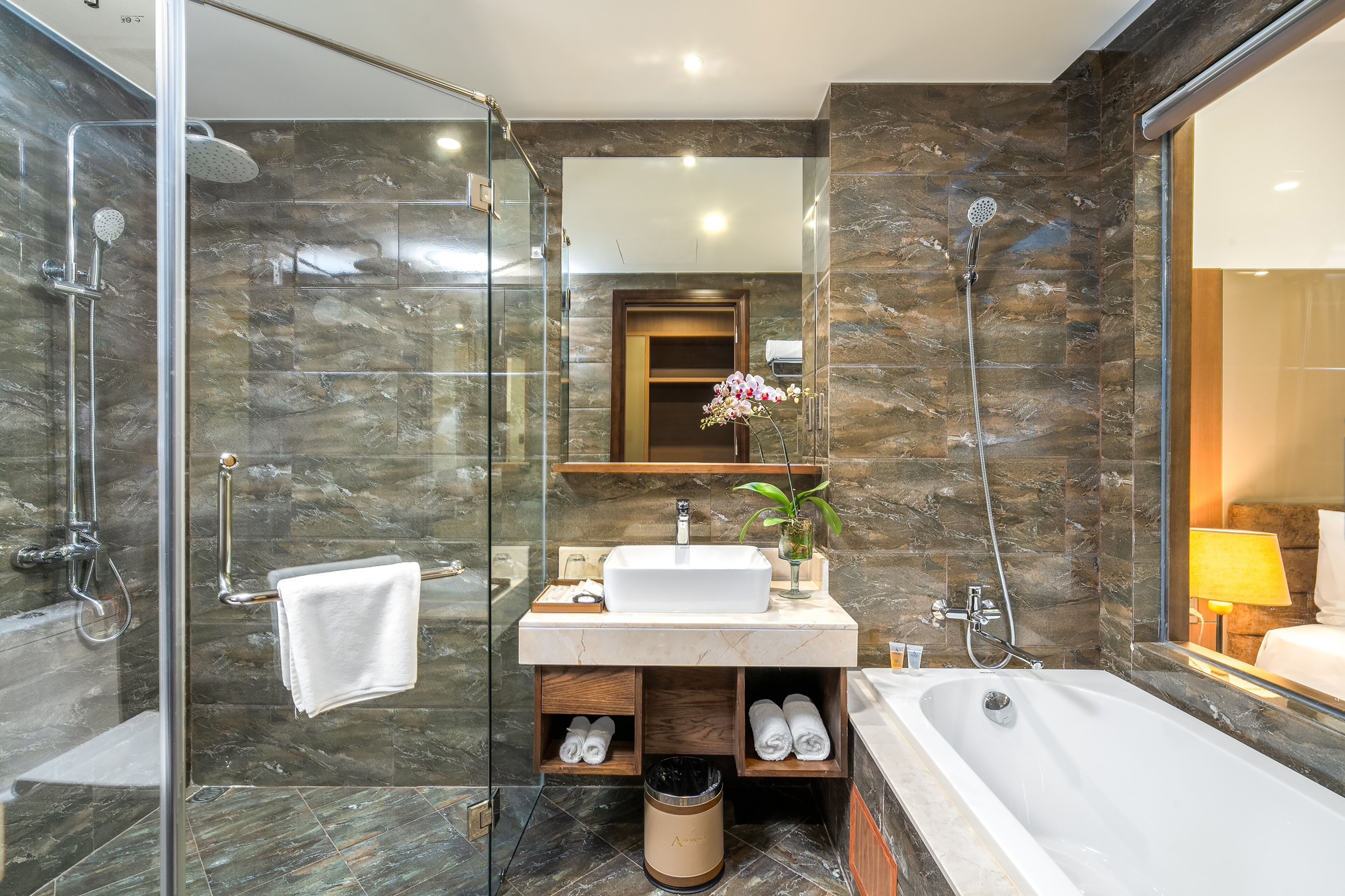 Un baño moderno con ducha de vidrio, una bañera grande y un tocador con lavamanos y espejo.