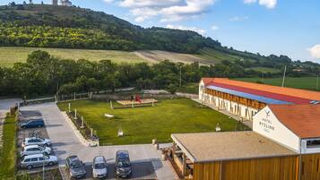 A hotel with a red roof, a parking area with several cars, and a playground.