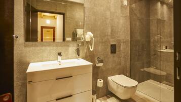 A modern bathroom with a large mirror, a sink, a toilet, and a shower area.