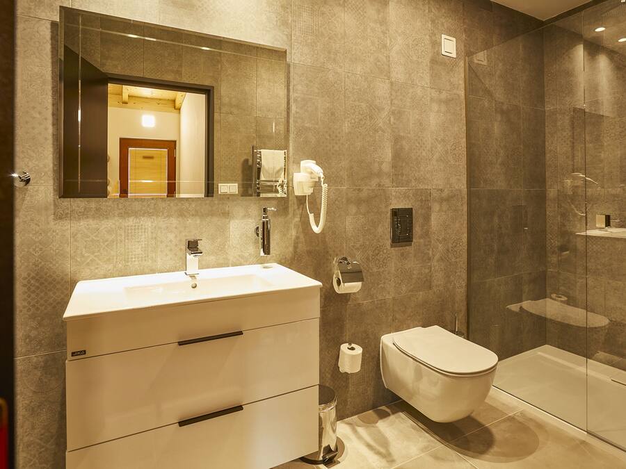A modern bathroom with a large mirror, a sink, a toilet, and a shower area.