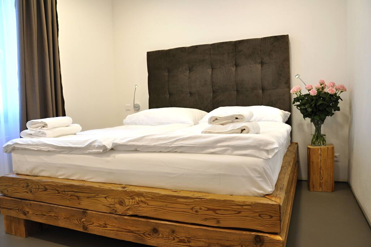 A wooden bed with white linens and a dark headboard in a hotel room.