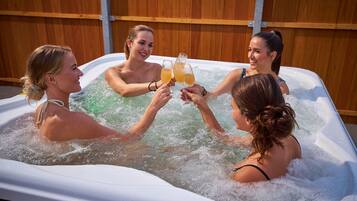 Un grupo de personas en un jacuzzi con una valla de madera al fondo.
