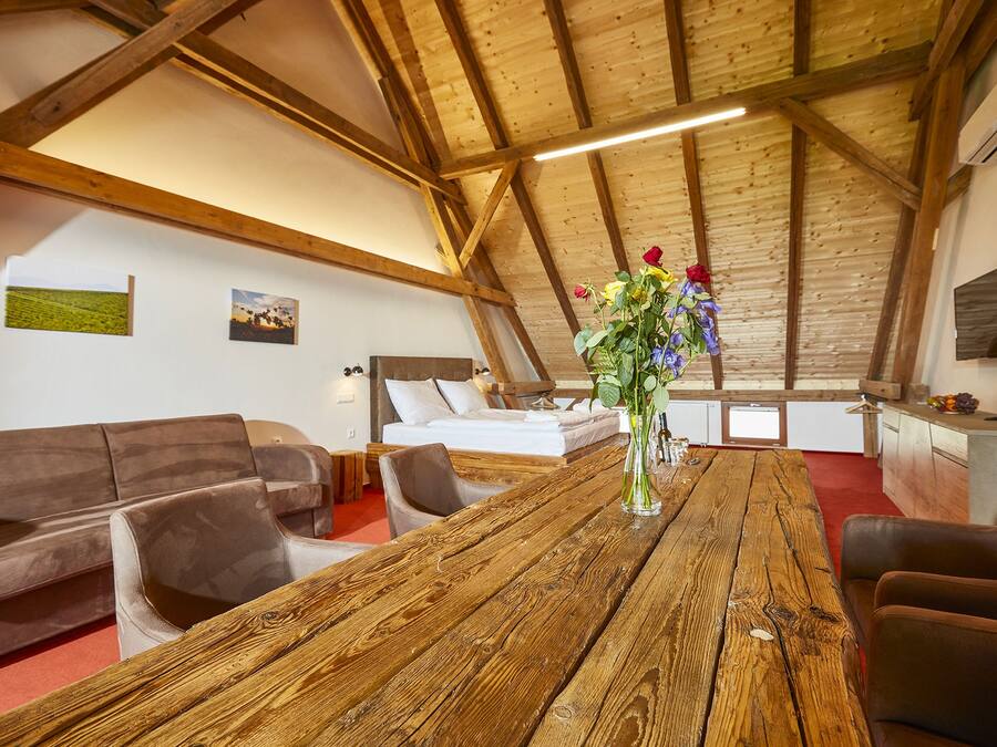 Una habitación acogedora con techo de madera, una gran mesa de madera, un sofá y una cama.