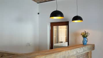 A reception area with a wooden counter, two black pendant lights, and a blue vase with flowers.
