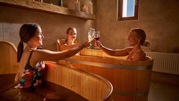 Relax in a serene spa setting with a bathtub, surrounded by candles and wooden beams.