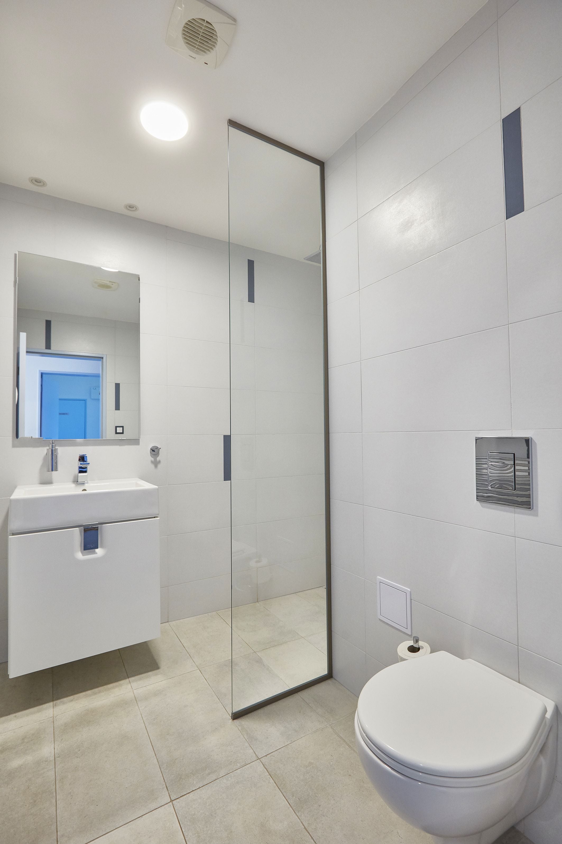 A modern bathroom with a glass shower enclosure, a white sink with a mirror, and a toilet.