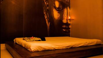 A bedroom with a large bed, a wooden headboard, and a wall-mounted light fixture.