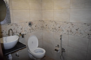 A bathroom with a sink, toilet, and shower. - Hotel Shyam Palace (Bhuj)