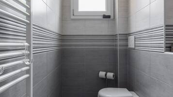 A modern bathroom with a toilet, bidet, and a window.