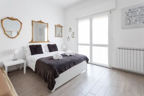 A modern bedroom with a large bed, white nightstands, and a window with a view. - Bologna Suite (Bologna)