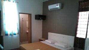 Un dormitori amb un llit, una tauleta de nit, un aparell d'aire condicionat, una finestra amb cortines i una porta.