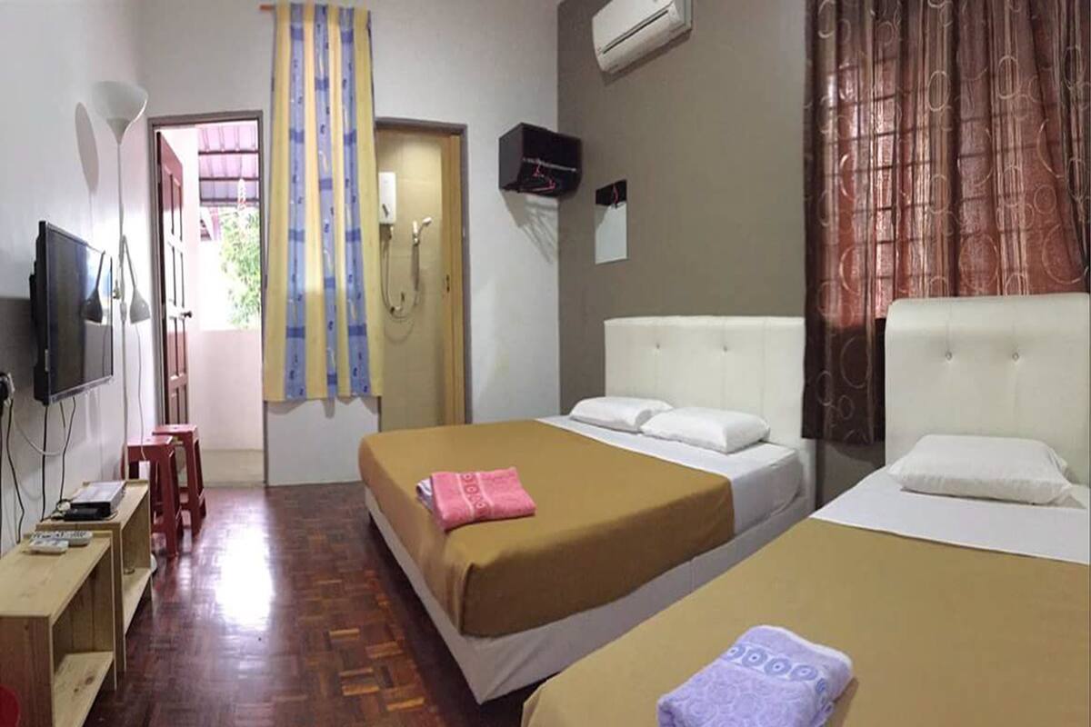 Une chambre d’hôtel avec deux lits, une télévision, un bureau et un plancher en bois.