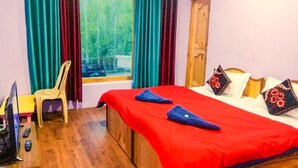 A room with a bed, a chair, a TV, and a window with curtains. - Galaxy Guest House (Leh)