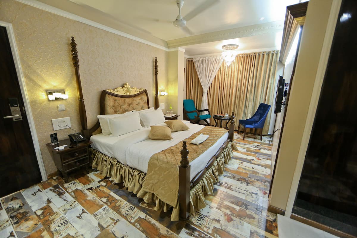 A hotel room with a large bed, a nightstand, a chair, and a small table.