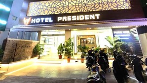 Un hotel llamado "Hotel President" con un diseño moderno, destacando una entrada imponente y un estacionamiento con motocicletas.
