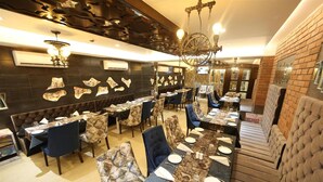 Un restaurante con una larga mesa compartida, cabinas individuales y un muro decorado.