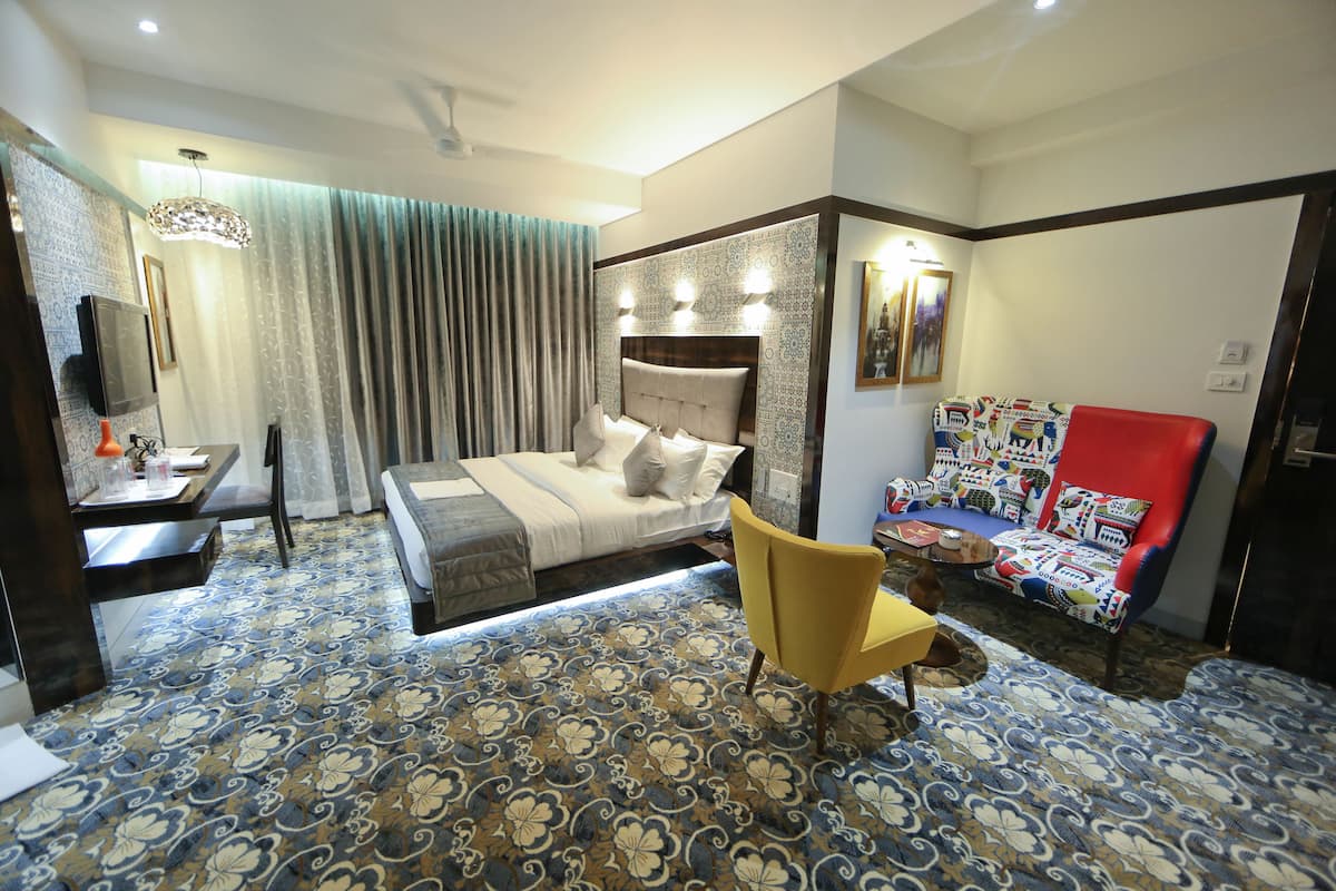 A hotel room with a bed, a desk, a chair, and a sofa.