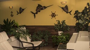 A room with a seating area featuring two chairs, a small table, and several potted plants. - Hotel Brisamar (Gozon)