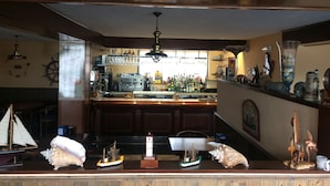 A bar area with a counter, various bottles, a ship model, and a lighthouse model. - Hotel Brisamar (Gozon)