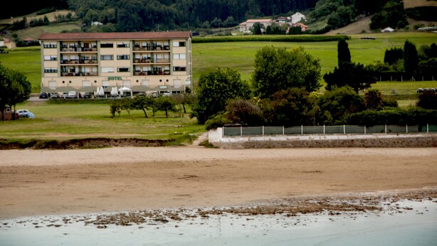 A hotel with multiple floors, outdoor seating, and a view of a beach and greenery. - Hotel Brisamar (Gozon)