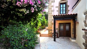 A stone pathway leading to a building with a wooden door and a window. - Elia Traditional Hotel & Spa (Platanias)