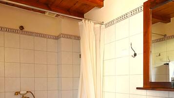 A bathroom with a shower, toilet, sink, and wooden ceiling.