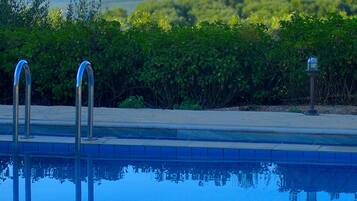 Una piscina al aire libre, sombrillas, sillones reclinables de piscina