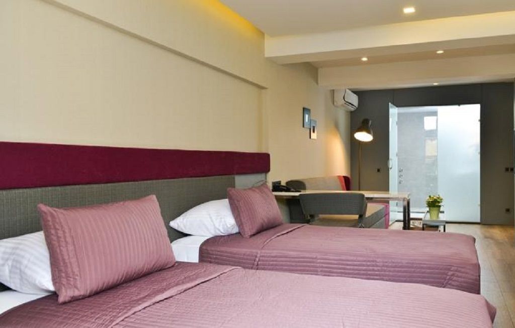 A hotel room with two beds, a desk, and a chair.