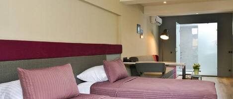 A hotel room with two beds, a desk, and a chair.