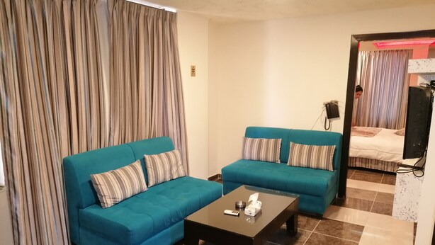 A living room with two blue sofas, a coffee table, and striped curtains. - Milano Hotel Suites (Amman)