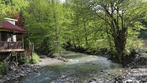 A riverside wooden structure with a stone foundation, surrounded by lush greenery and a flowing river. - Abant Dort Mevsim Konagi (Bolu)
