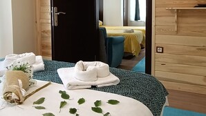 A hotel room with a bed, a TV mounted on the wall, and a wooden door leading to another room. - Abant Dort Mevsim Konagi (Bolu)
