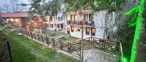 Un patio con un sendero de piedra, cerca de madera y un edificio con balcón.