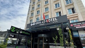 The Grand Hotel building facade with multiple windows and balconies, a prominent entrance with a sign, and a coffee shop named "Coffee Bean" in front. - Grand Hotel Van (Van)