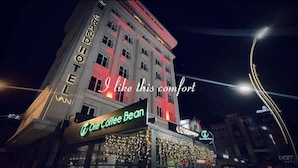 A hotel with a prominent 'Grand Hotel' sign, a 'One Coffee Bean' shop, and a 'Coca-Cola' sign. - Grand Hotel Van (Van)