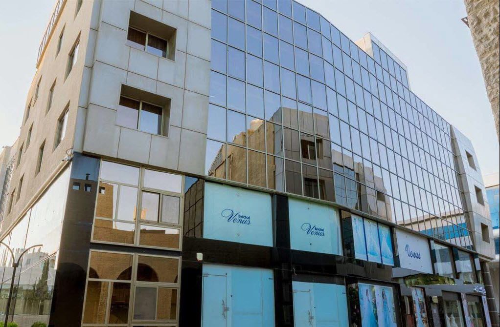 A modern building with a glass facade and multiple balconies.