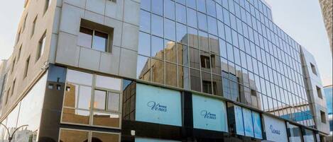 A modern building with a glass facade and multiple balconies.