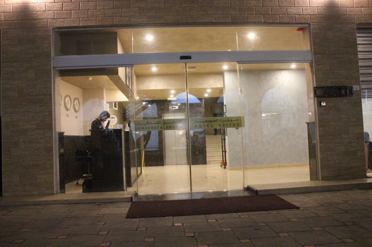 A hotel entrance with a glass door, a reception desk, and a sign indicating hotel suites.